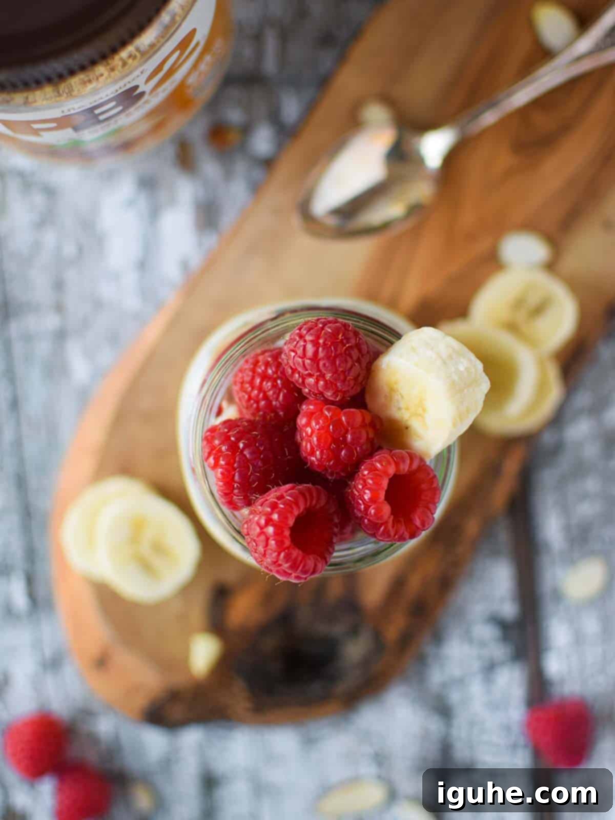 Protein-Packed PB2 Overnight Oats 3 Overhead picture of overnight oats in a jar on a wood surface with raspberries on top, ready to eat.