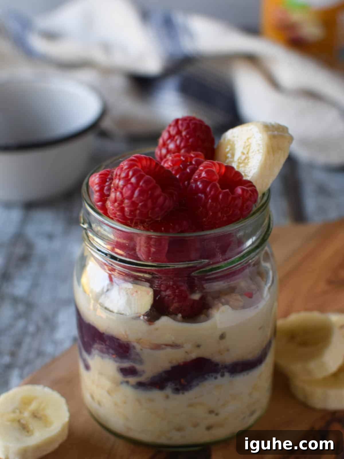 Protein-Packed PB2 Overnight Oats 4 Close-up of peanut butter overnight oats in a jar with raspberries and bananas, showing the creamy texture and jam layers.
