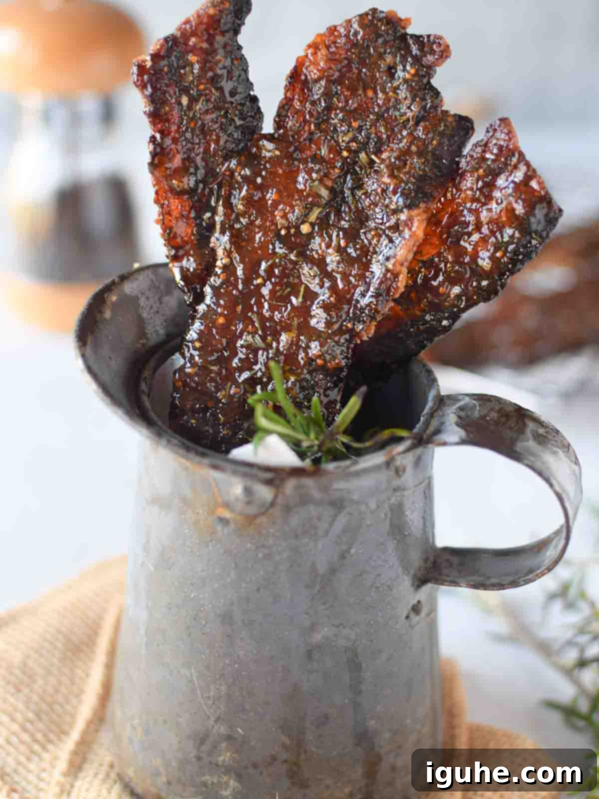 Sweet & Savory Fig-Rosemary Bacon 3 Candied bacon with rosemary and fig in a metal serving pitcher, ready to be enjoyed.