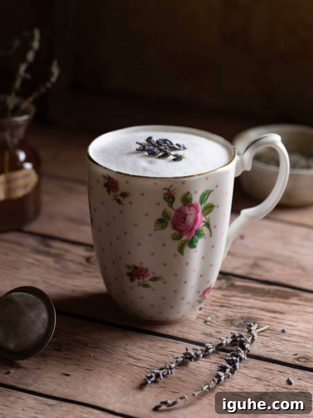 Lavender tea latte in a floral mug on top of a wood surface.