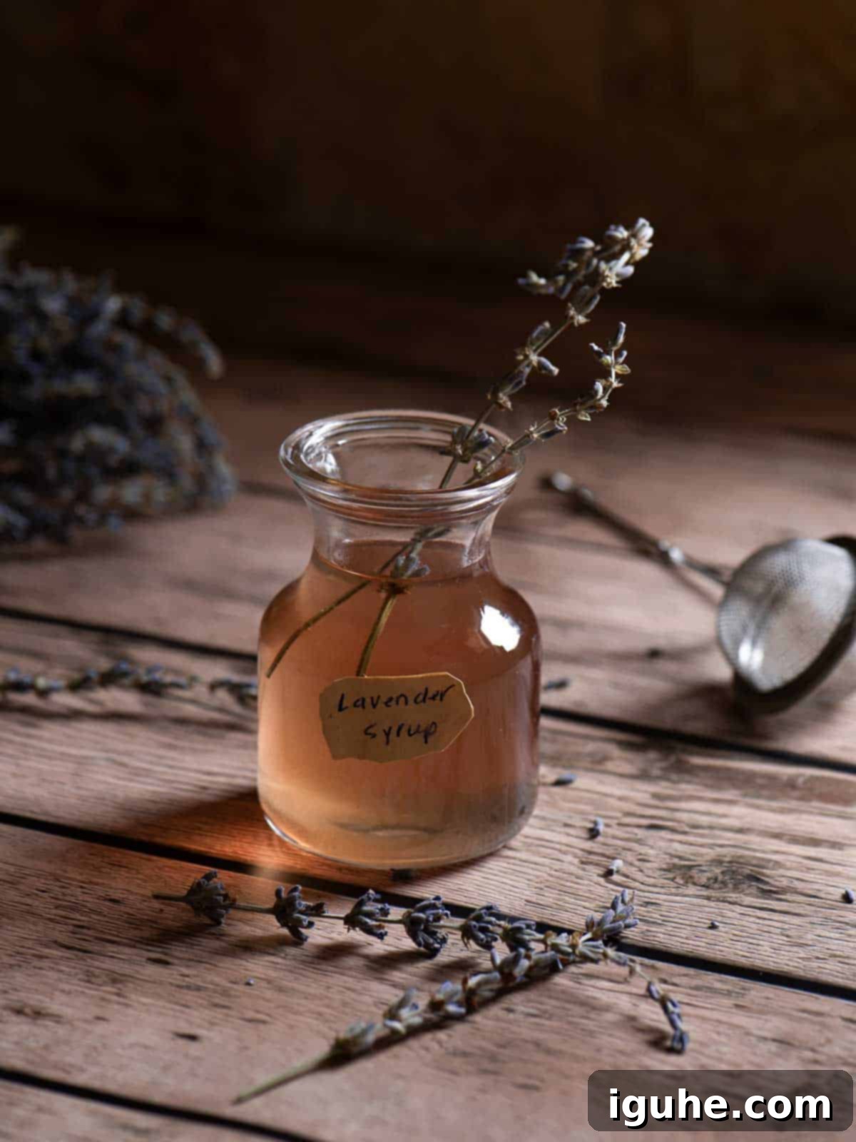 Lavender Bliss Latte 3 Lavender syrup in a clear container on a wood surface with lavender buds in it.