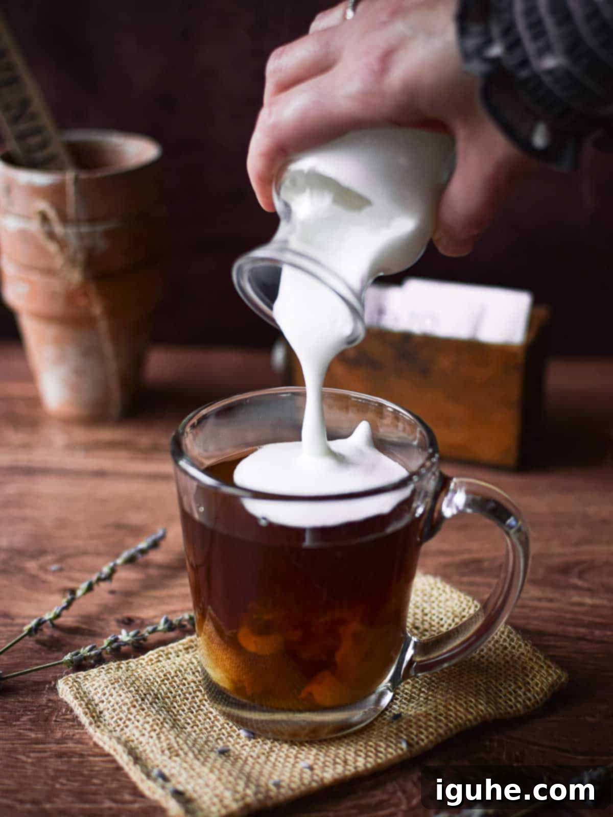 Lavender Bliss Latte 4 Angled view of frothed milk being poured into a glass with tea to make a lavender tea latte.