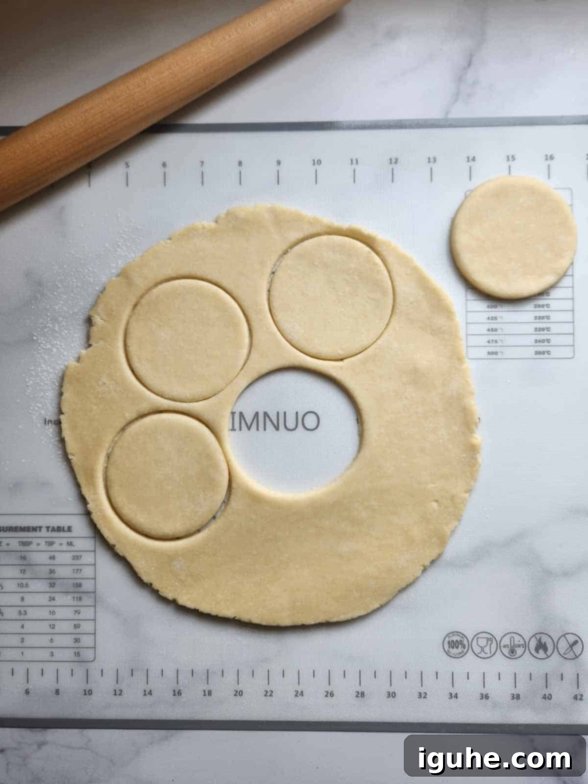 Pie dough being carefully cut into uniform circles on a lightly floured surface, ready for filling.