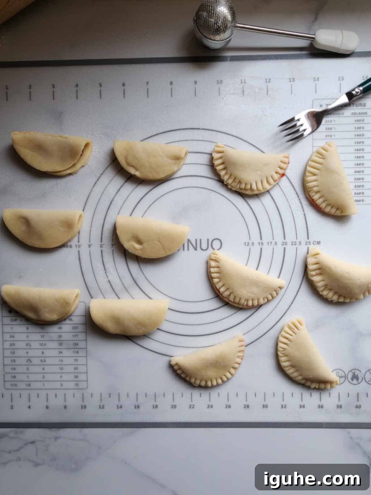 Rose Infused Strawberry Pie Bites 6 Pie dough circles folded in half and being crimped with a fork for making mini pies.