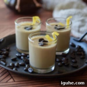 Velvet Espresso Panna Cotta 9 A close-up of a single serving of espresso panna cotta in a small glass jar, garnished with whole coffee beans and a lemon rind twist, emphasizing its rich texture and elegant presentation.