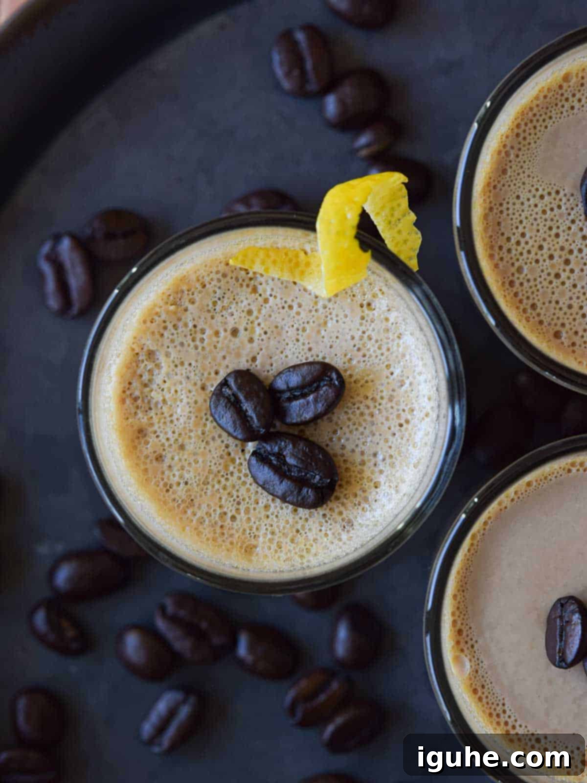 Velvet Espresso Panna Cotta 3 Overhead view of espresso coffee panna cotta in a clear glass jar, topped with whole roasted coffee beans and a delicate lemon rind twist, emphasizing its rich color and elegant garnish.