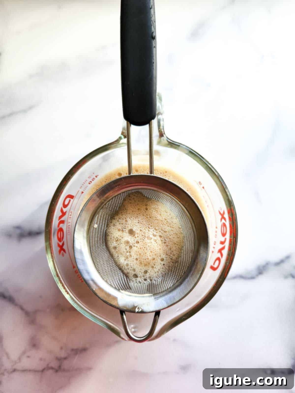 Velvet Espresso Panna Cotta 7 Espresso panna cotta liquid being carefully strained through a fine mesh sieve into a serving cup, demonstrating a step to ensure a perfectly smooth dessert.