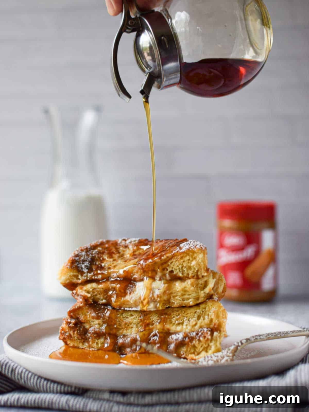 Golden brown Biscoff Stuffed French Toast drizzled generously with maple syrup.