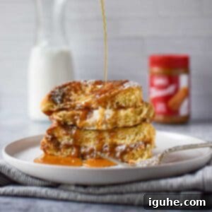 Decadent Biscoff Stuffed French Toast 7 Biscoff stuffed French toast drizzled with maple syrup on a white plate, ready to be served.