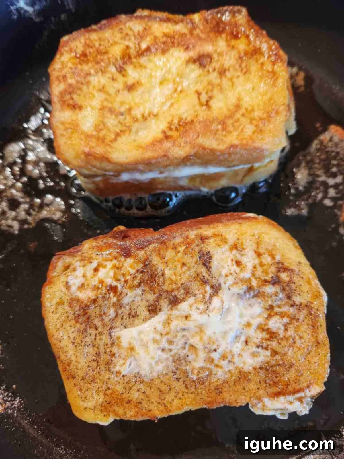 Decadent Biscoff Stuffed French Toast 5 Stuffed French toast sandwiches cooking on a hot, buttered griddle, achieving a perfect golden brown.