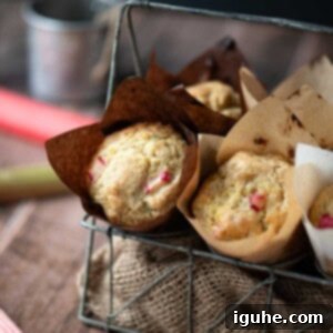 Tangy Rhubarb Muffins 10 Rhubarb muffins in a metal basket with stalks of rhubarb to the side.