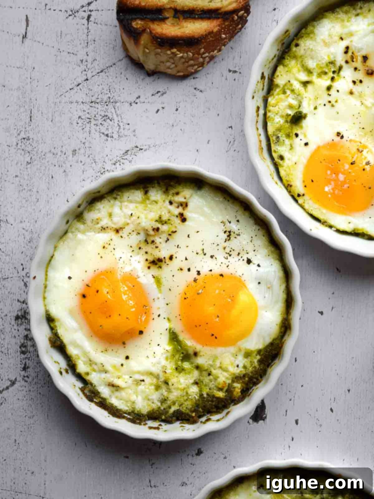 Pesto Egg Bake 3 Overhead view baked eggs with pesto in white ramekins.