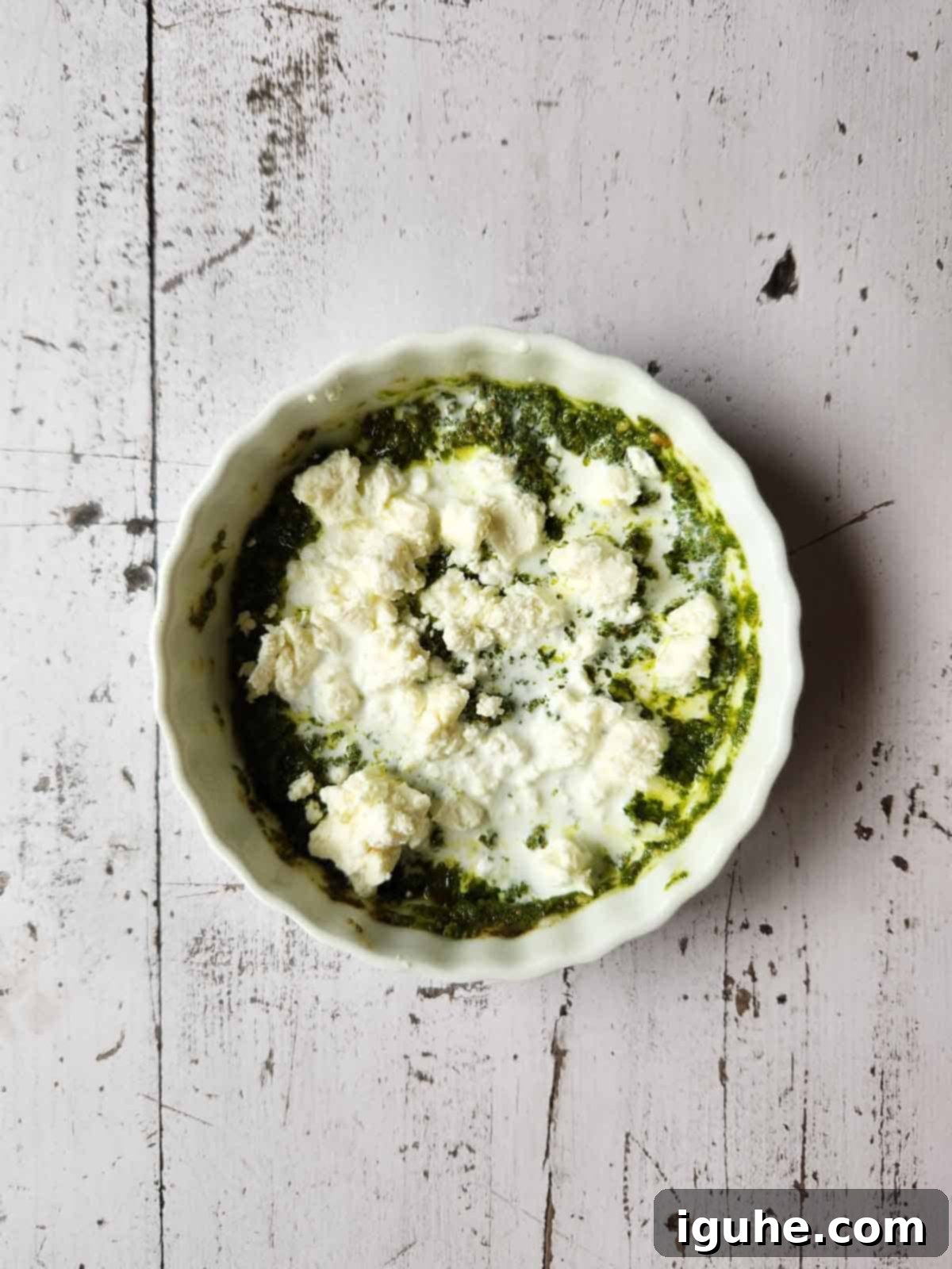 Pesto Egg Bake 6 Pesto sauce, feta and cream in a white ramekin.