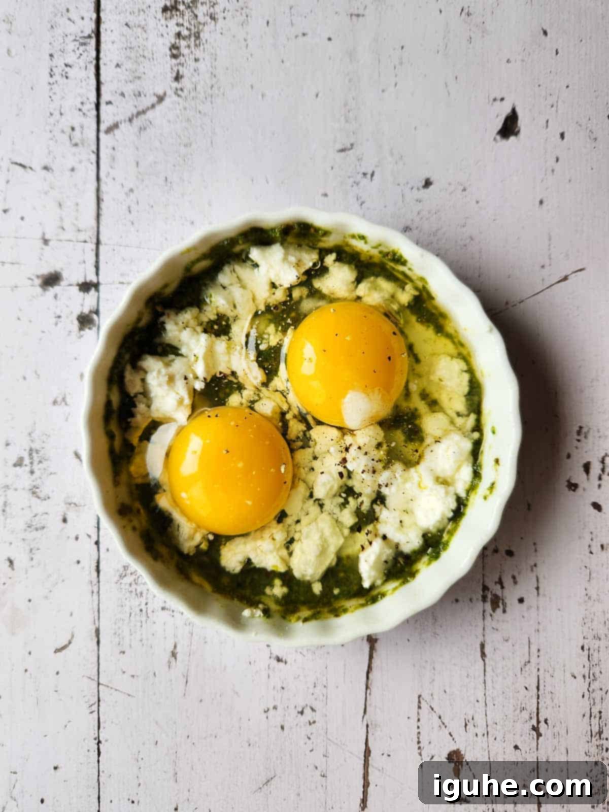 Pesto Egg Bake 7 Pesto, feta, cream, and two eggs in a white ramekin.