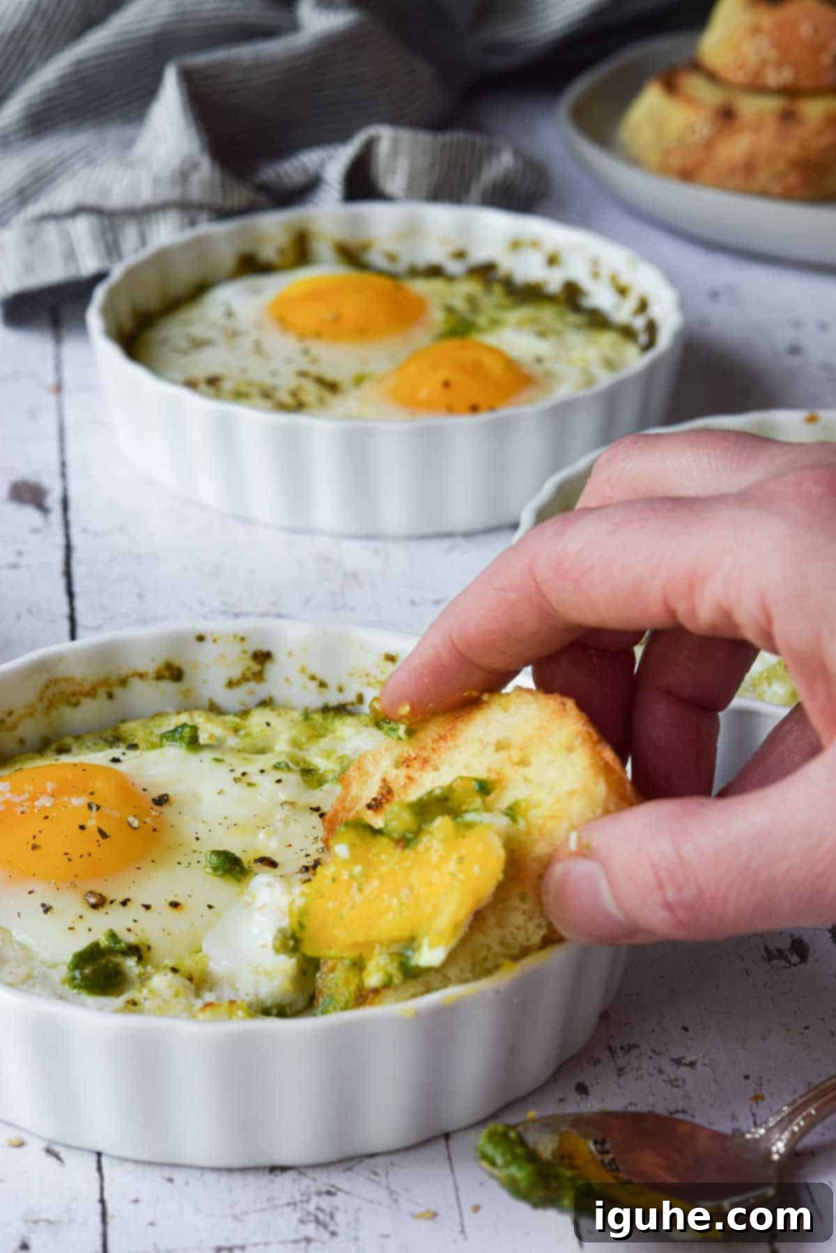 Pesto Egg Bake 8 Bread being dunked in baked eggs in a ramekin.