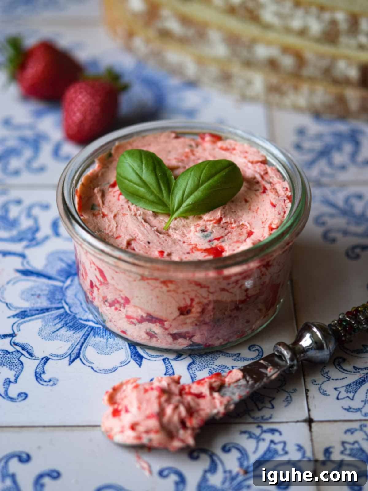 Whipped strawberry basil butter in a glass jar on a tile background, ready to be served or stored.