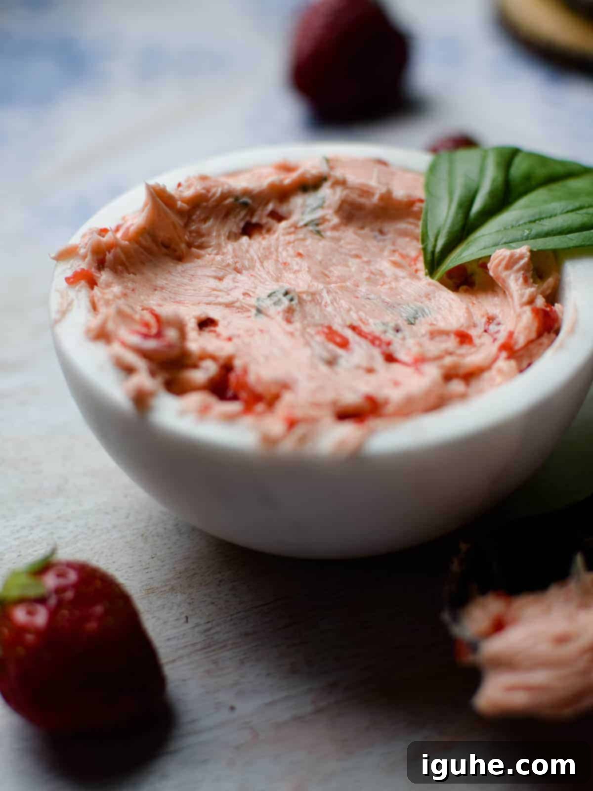 Strawberry Basil Cloud Butter 3 Close-up of fluffy, light pink whipped strawberry and basil butter in a white bowl, showcasing its smooth texture.