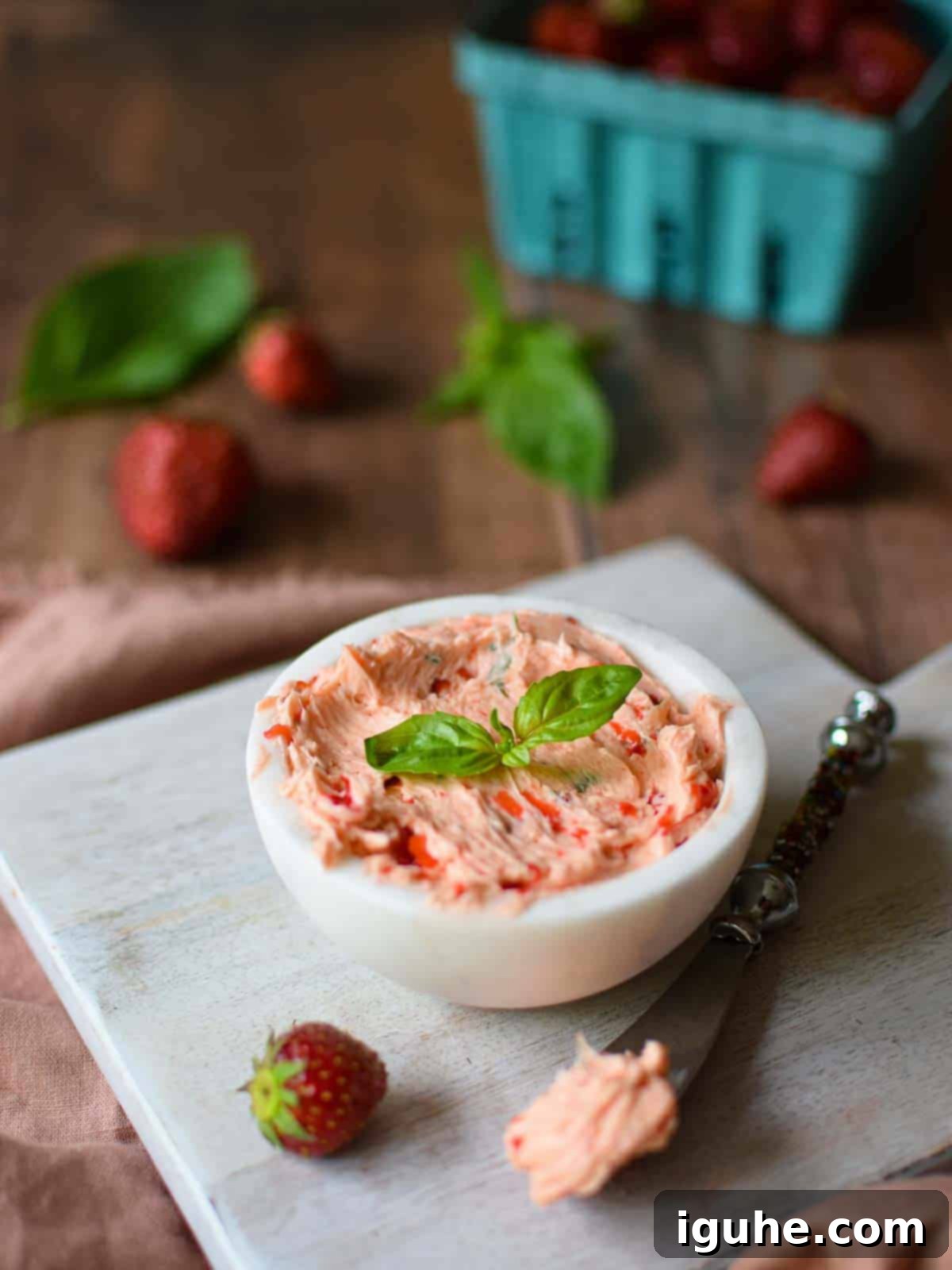 Strawberry Basil Cloud Butter 8 Whipped strawberry butter in a white bowl, garnished with fresh basil, on a rustic wooden background.