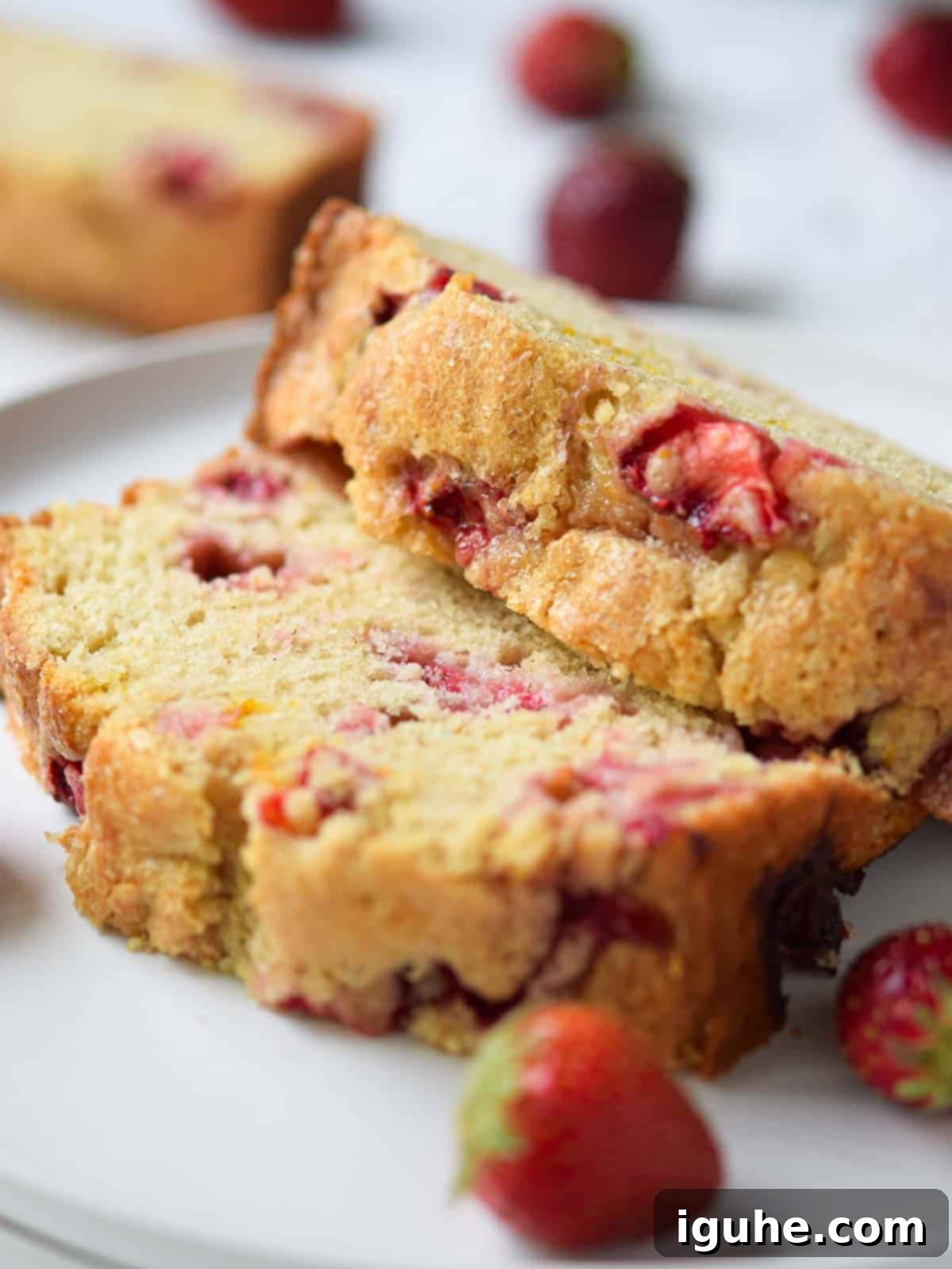 Buttermilk Kissed Strawberry Loaf 8 Close-up of a perfectly sliced piece of moist strawberry buttermilk bread on a white plate, showing the soft crumb and berry pieces.
