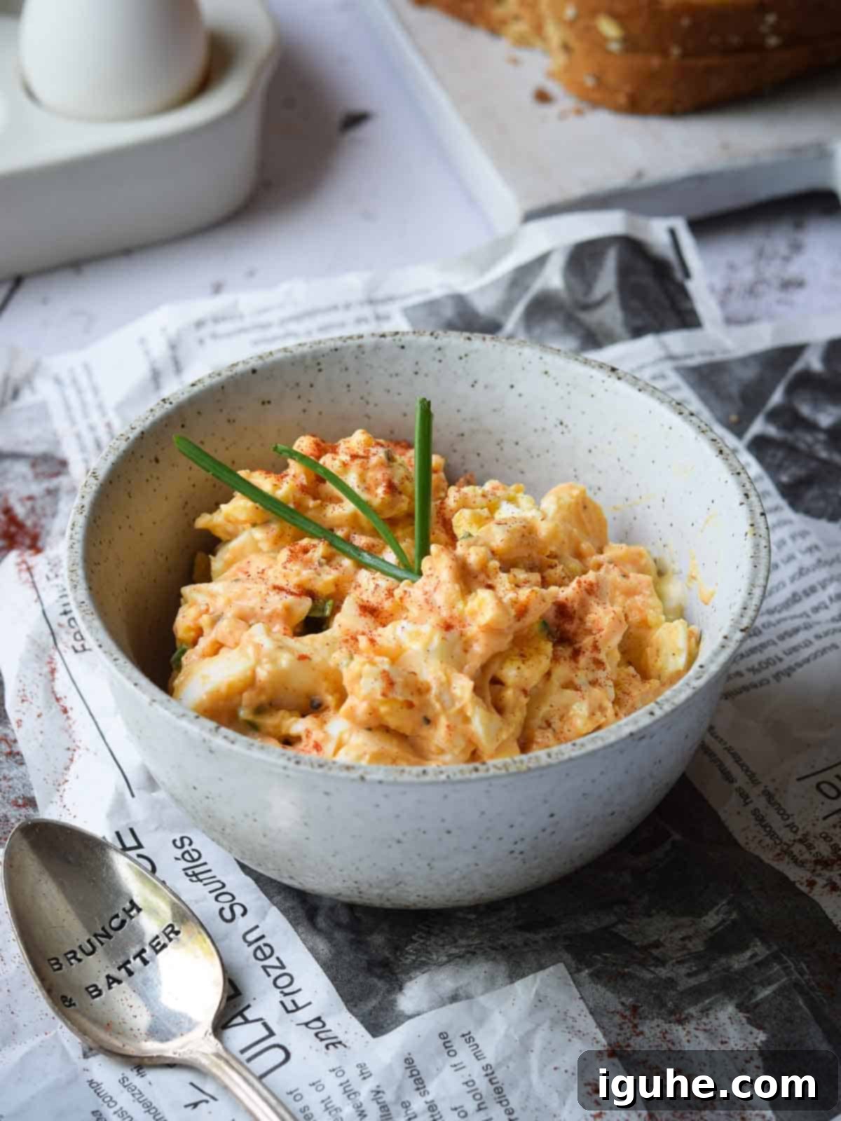Smoky Paprika and Fresh Chive Egg Salad 2 Close up of creamy egg salad in a bowl, generously sprinkled with vibrant smoked paprika and fresh green chives, ready to be served.