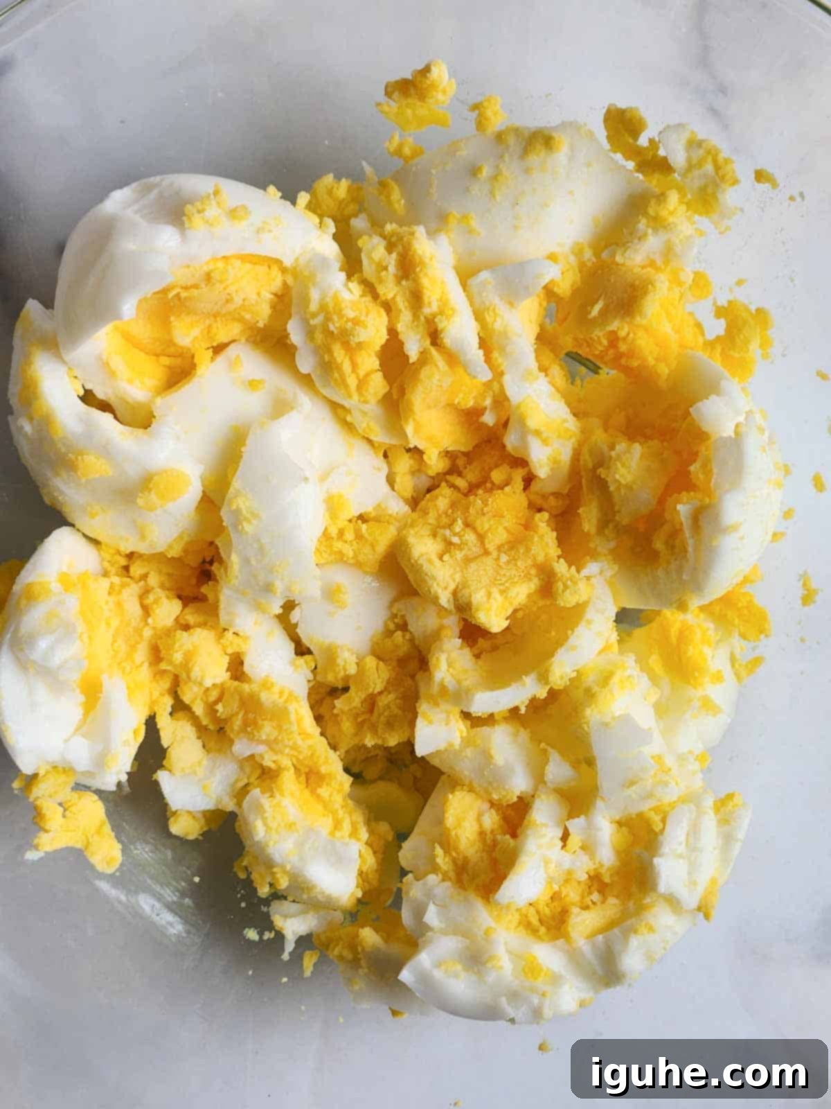 Smoky Paprika and Fresh Chive Egg Salad 5 Close up of coarsely chopped hard-boiled eggs in a bowl, showing a mix of whites and yolks, ready for mixing.