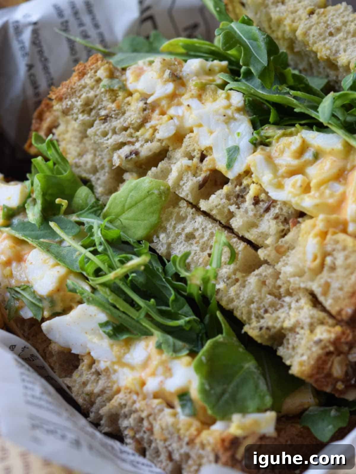 Smoky Paprika and Fresh Chive Egg Salad 8 A freshly made egg salad sandwich in a rustic woven basket, ready for a picnic or lunch.