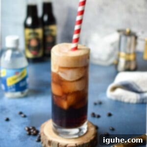 Espresso Sparkle 6 Espresso soda in a glass with a red straw on top of a blue surface.