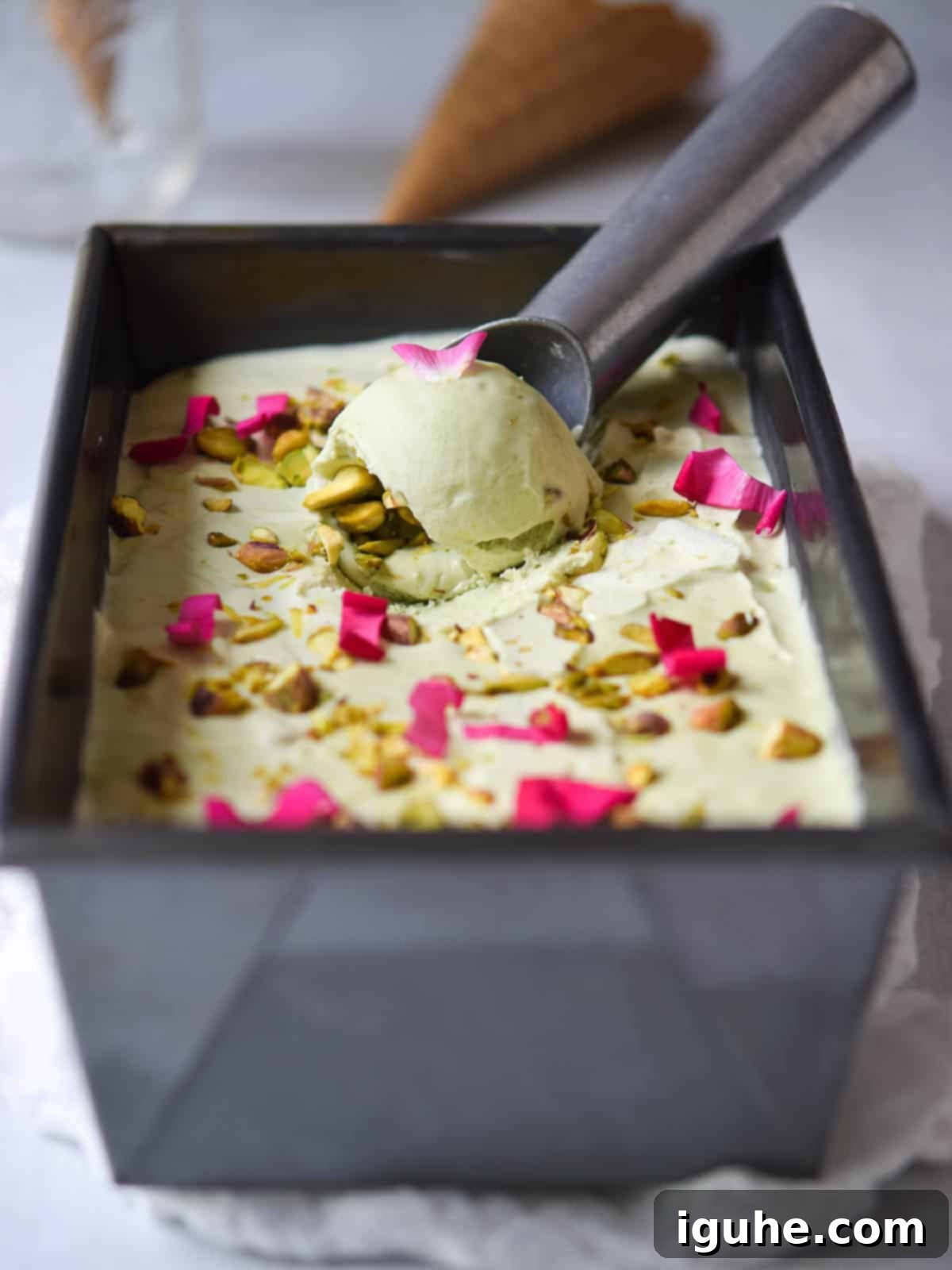 Effortless Pistachio Ice Cream 9 Pistachio ice cream artfully presented in a loaf pan, garnished with delicate rose petals, ready to be served.