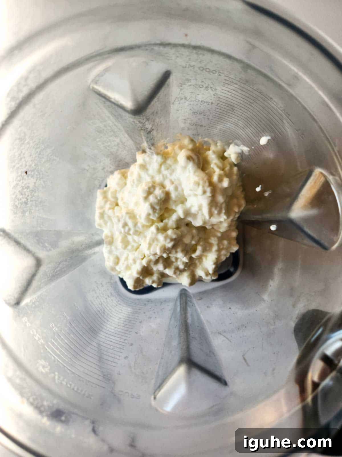 Creamy Cottage Cheese Breakfast Bowls 4 Close-up of cottage cheese being poured into a blender, illustrating the first step of the blending process.