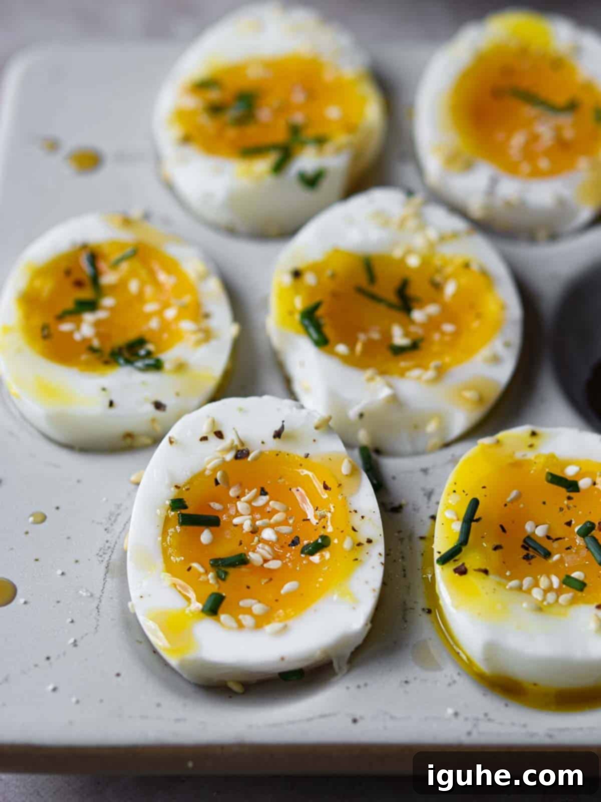 Soft-boiled eggs with sesame oil and toasted sesame seeds cut open on a platter.