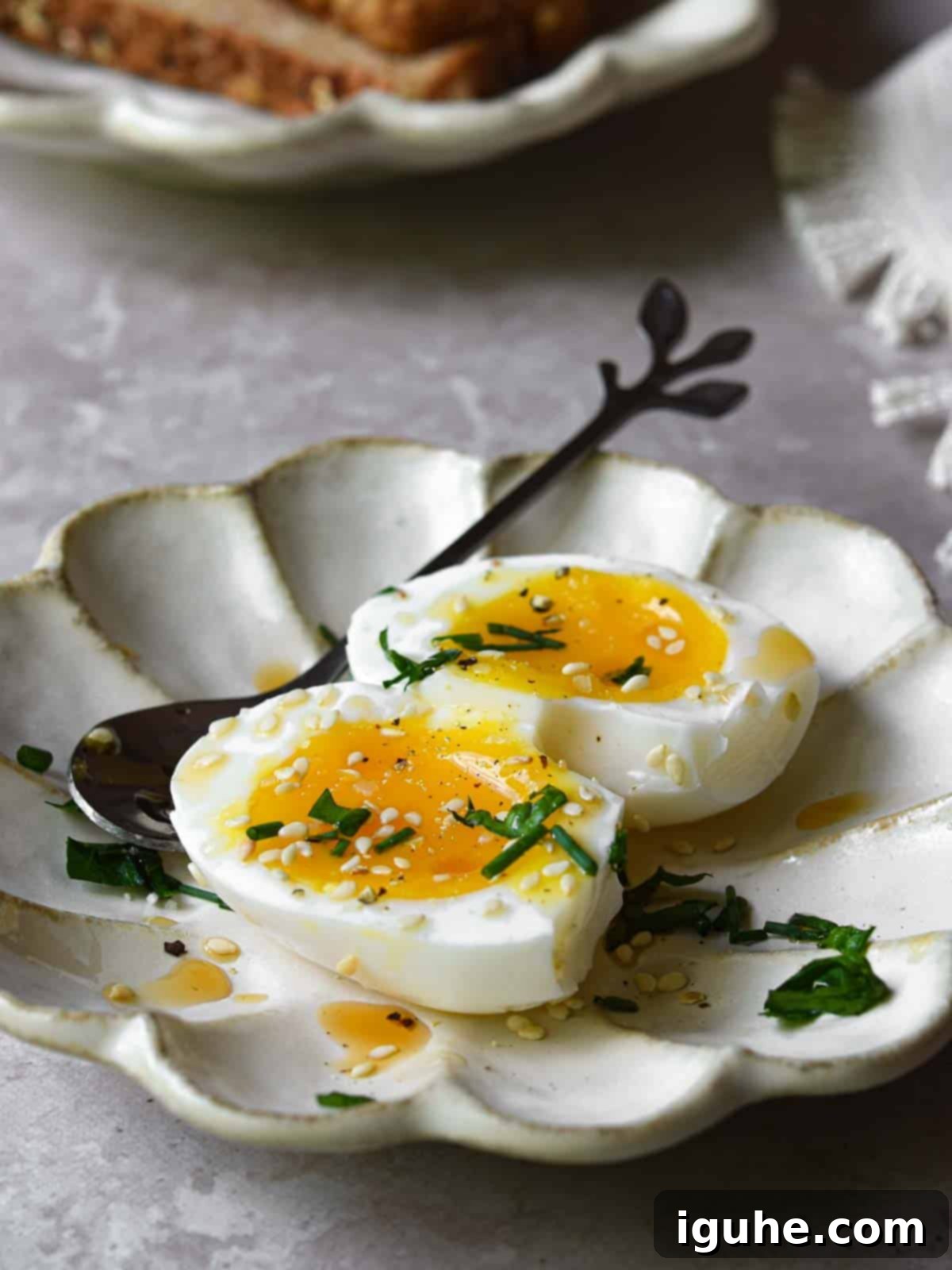 Sesame Kissed Jammy Eggs 3 Soft-boiled eggs with sesame oil and toasted sesame seeds cut open on a beige dish.