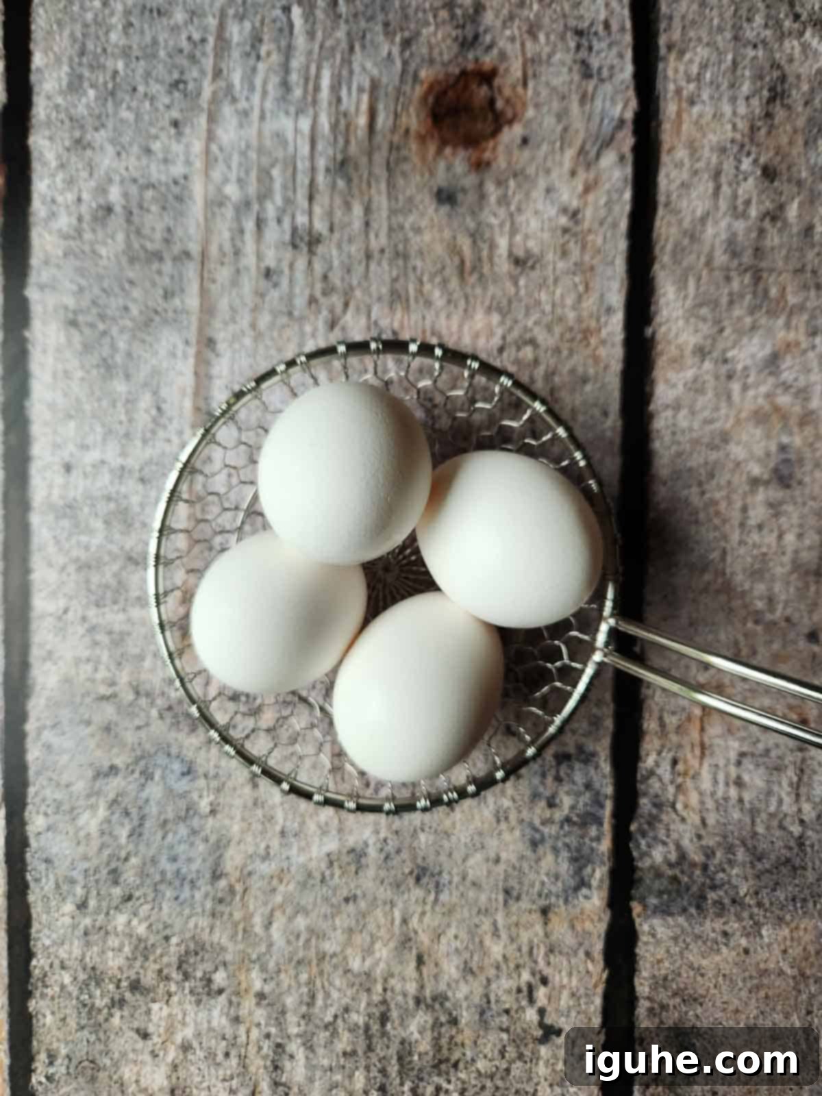 Sesame Kissed Jammy Eggs 4 Four eggs in a wire strainer.