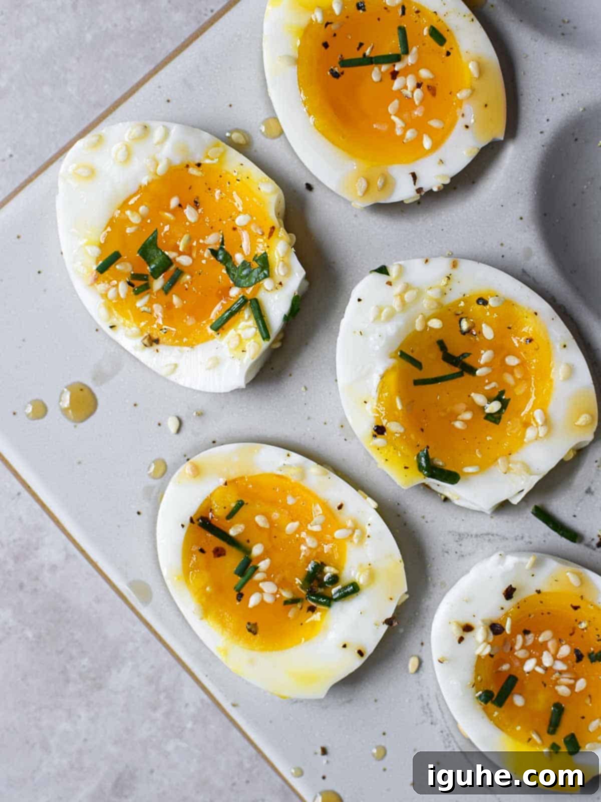 Sesame Kissed Jammy Eggs 8 Overhead view of soft-boiled eggs with sesame oil and toasted sesame seeds cut open.