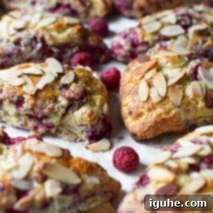 Buttery Raspberry Almond Scones 9 Close-up of baked raspberry almond scones on parchment paper, ready to be served.