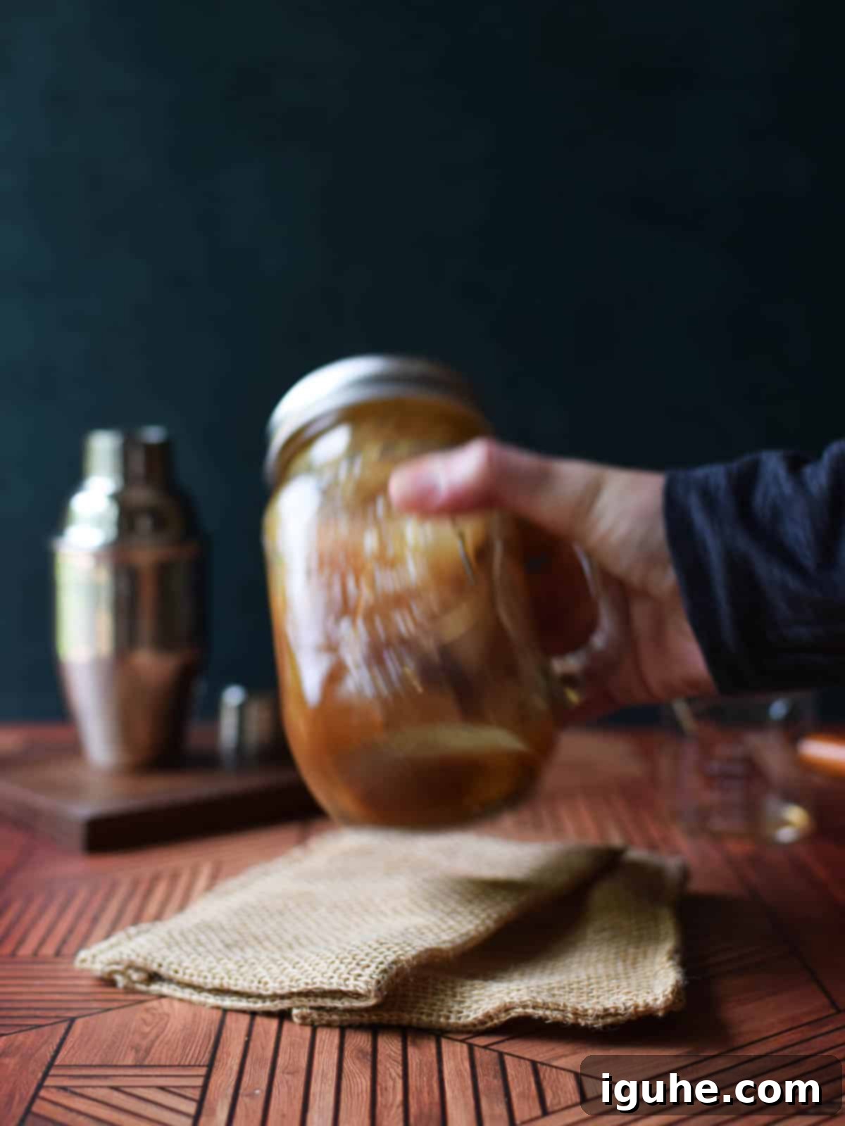Caramel-Kissed Shaken Chai 5 A hand vigorously shaking a lidded mason jar filled with ice, brown sugar syrup, and chai tea, creating foam.