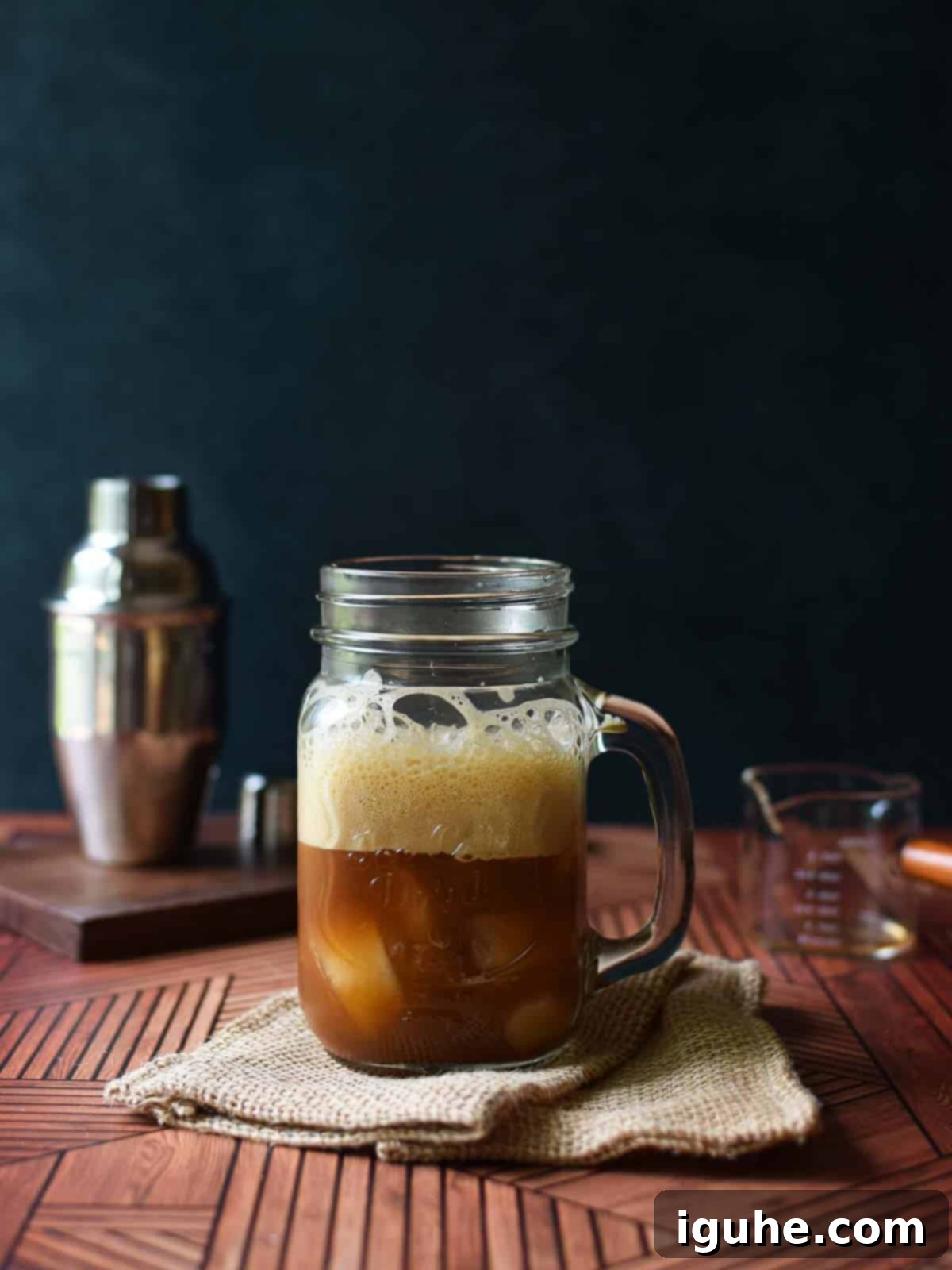 Caramel-Kissed Shaken Chai 6 A close-up of the frothy, amber-colored brown sugar shaken chai tea poured into a clear glass mug, showcasing its creamy texture.