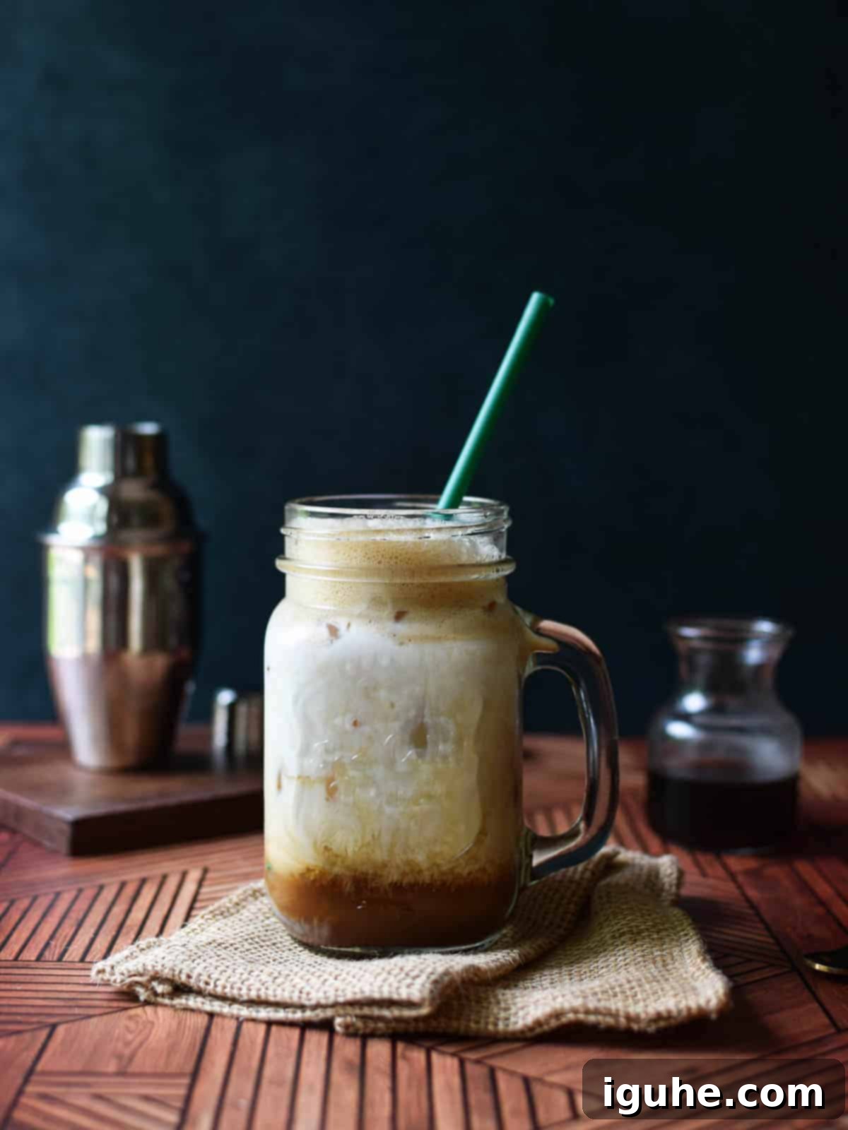 Caramel-Kissed Shaken Chai 10 A refreshing brown sugar shaken chai tea with milk and a green straw in a handled glass mug, ready to be enjoyed.