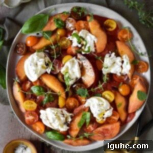 Peaches and Cream Burrata Caprese 10 Overhead view of a vibrant peach, tomato, and burrata salad on a round plate, showcasing its fresh summer ingredients.