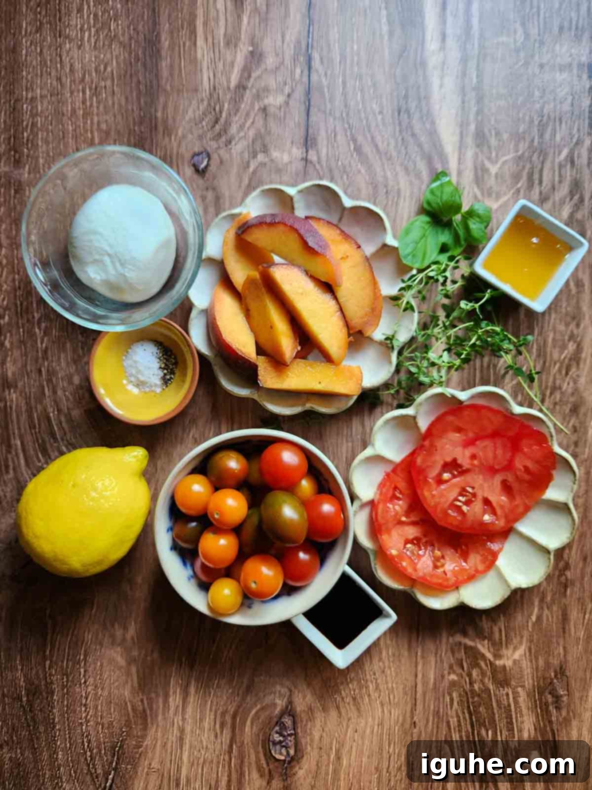 Peaches and Cream Burrata Caprese 4 All fresh ingredients for burrata peach salad, including tomatoes, peaches, burrata, and herbs, neatly arranged on a rustic wood background.