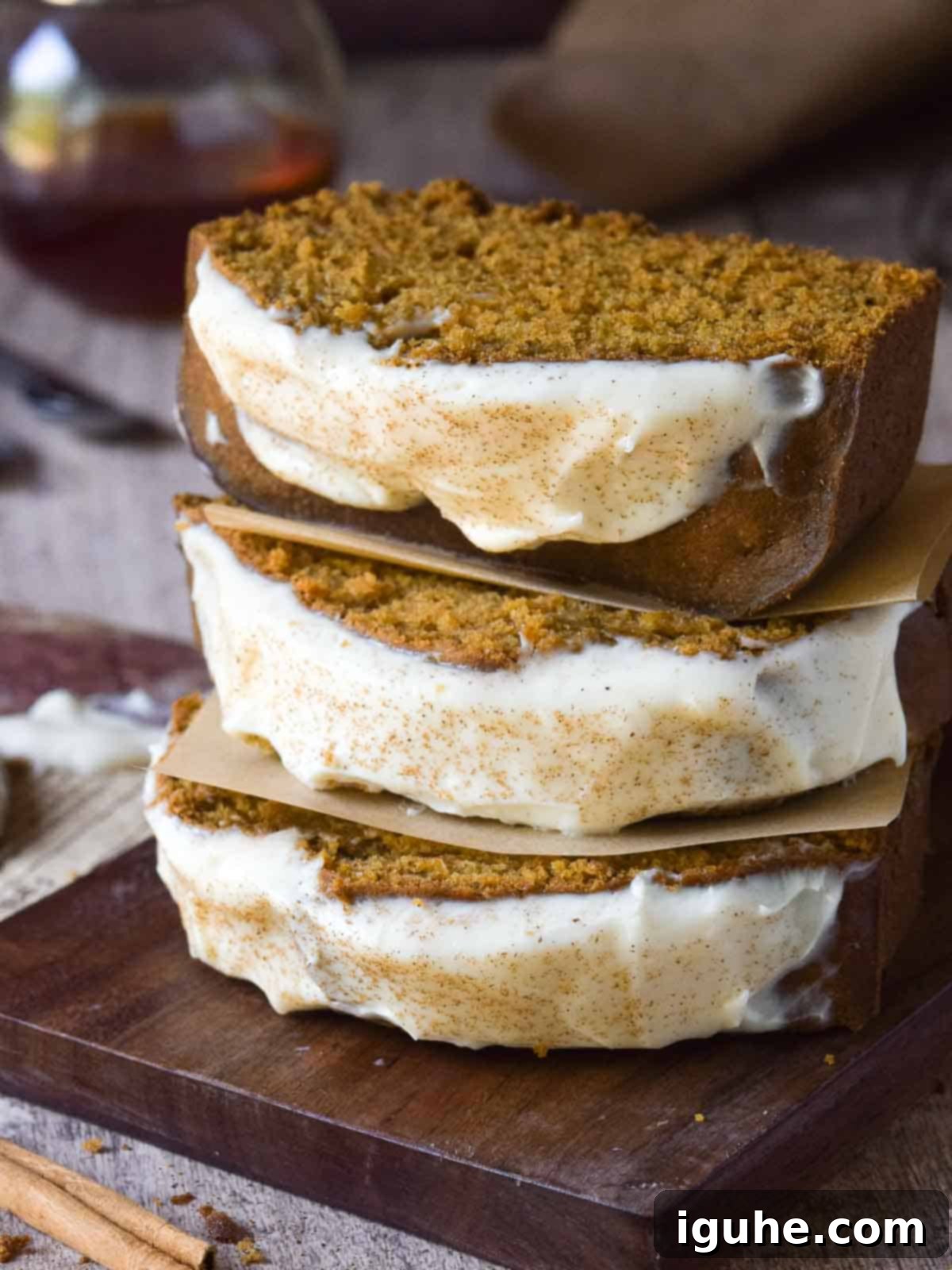 Three slices of pumpkin bread with maple cream cheese frosting stacked on top of each other.