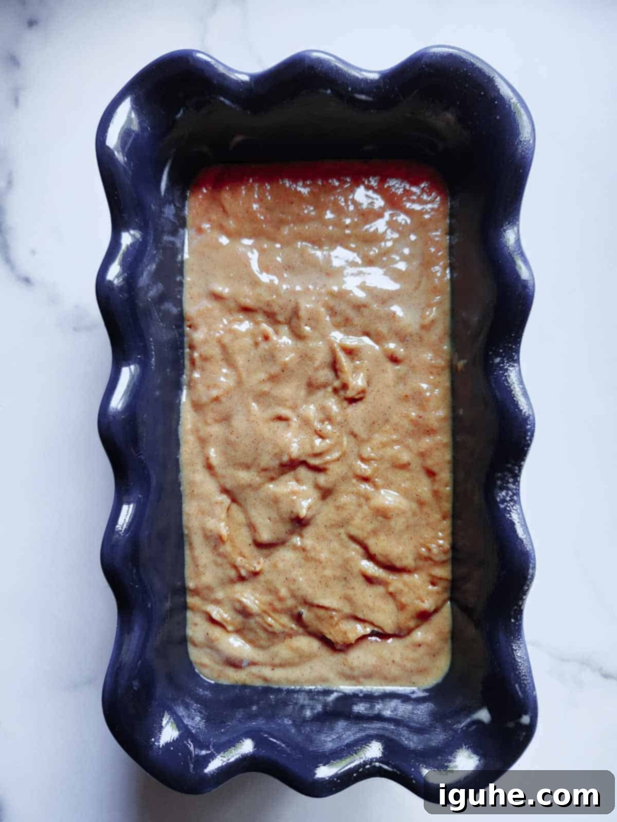 Warm Spiced Pumpkin Bread with Maple Cream Cheese Frosting 7 Prepared pumpkin bread batter in a blue loaf pan.
