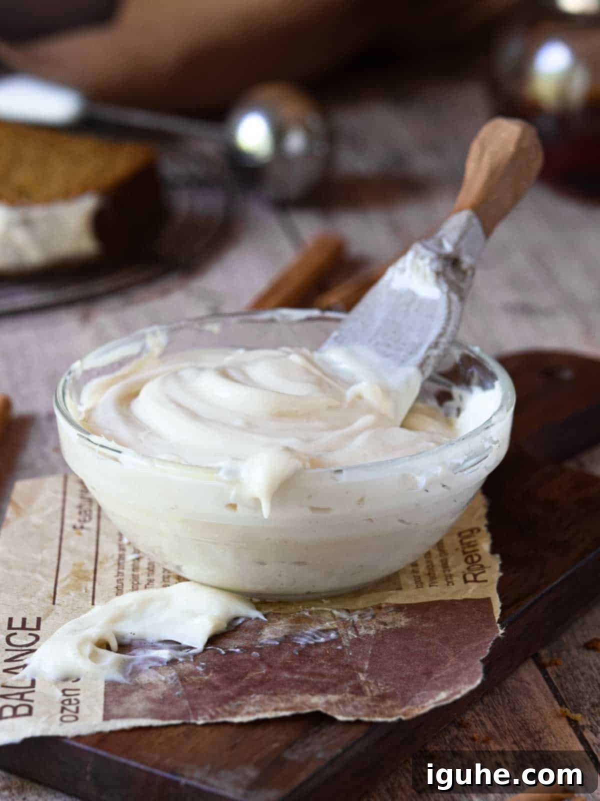Warm Spiced Pumpkin Bread with Maple Cream Cheese Frosting 8 Cream cheese frosting in a clear bowl on a wood surface.
