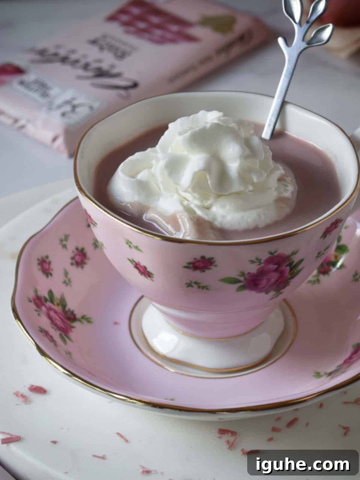 Velvet Ruby Hot Cocoa 8 Angled view of ruby hot chocolate with whipped cream in a pink floral cup, ready to be enjoyed.