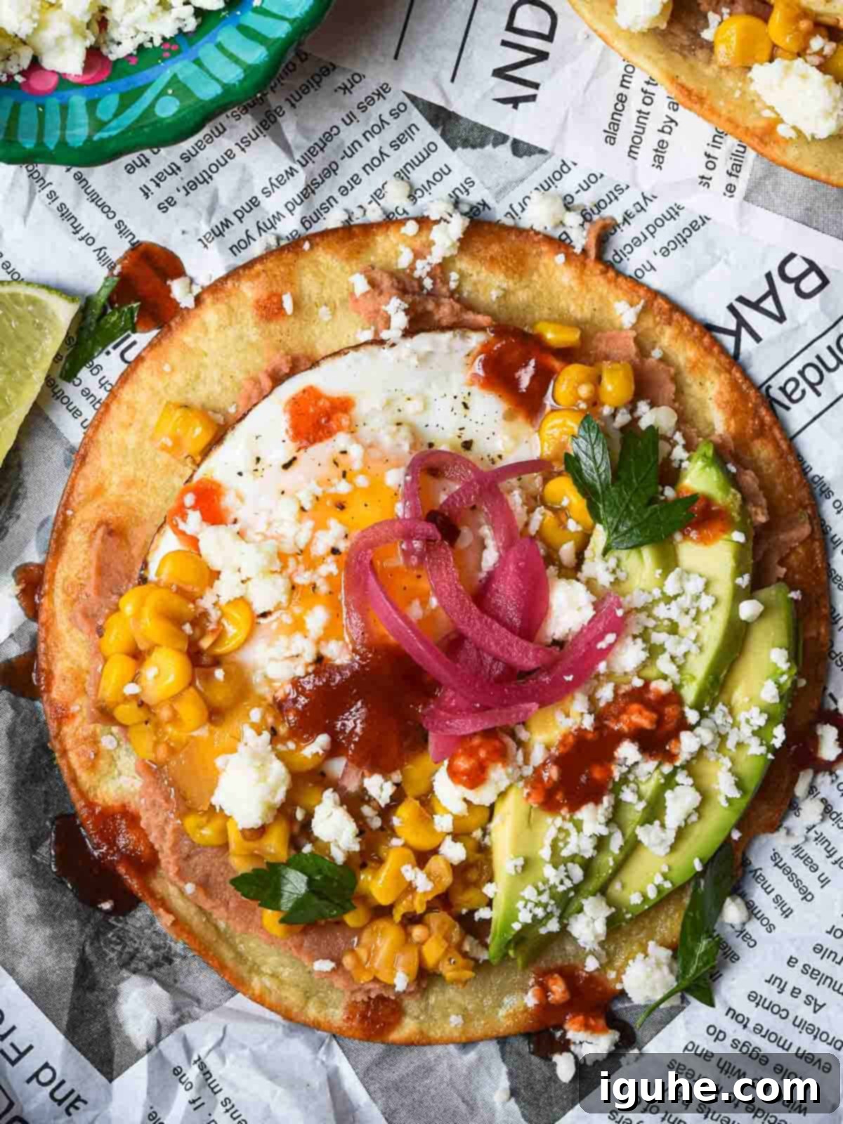 Quick and Delicious Huevos Rancheros Tostadas 8 Overhead view of a Mexican tostada with toppings on newspaper.
