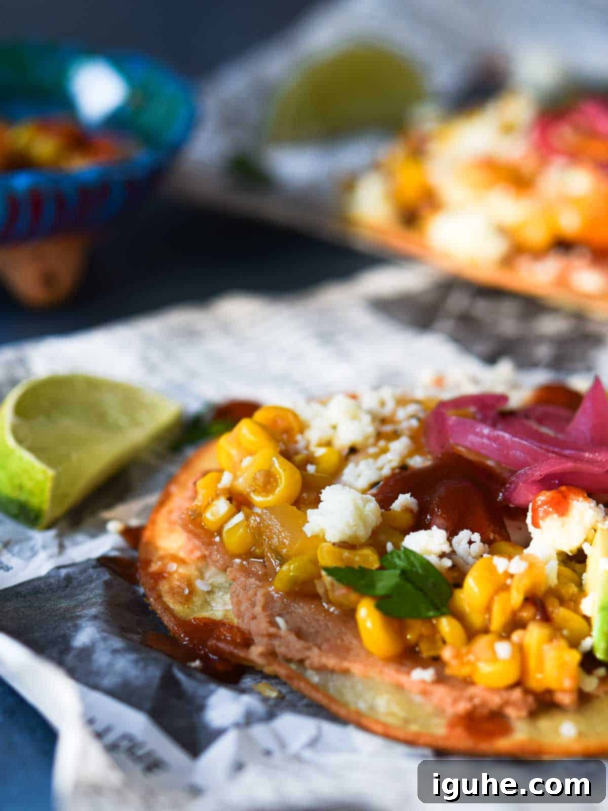 Quick and Delicious Huevos Rancheros Tostadas 9 Close-up of a Mexican Huevos Rancheros tostada on newspaper with a lime next to it.