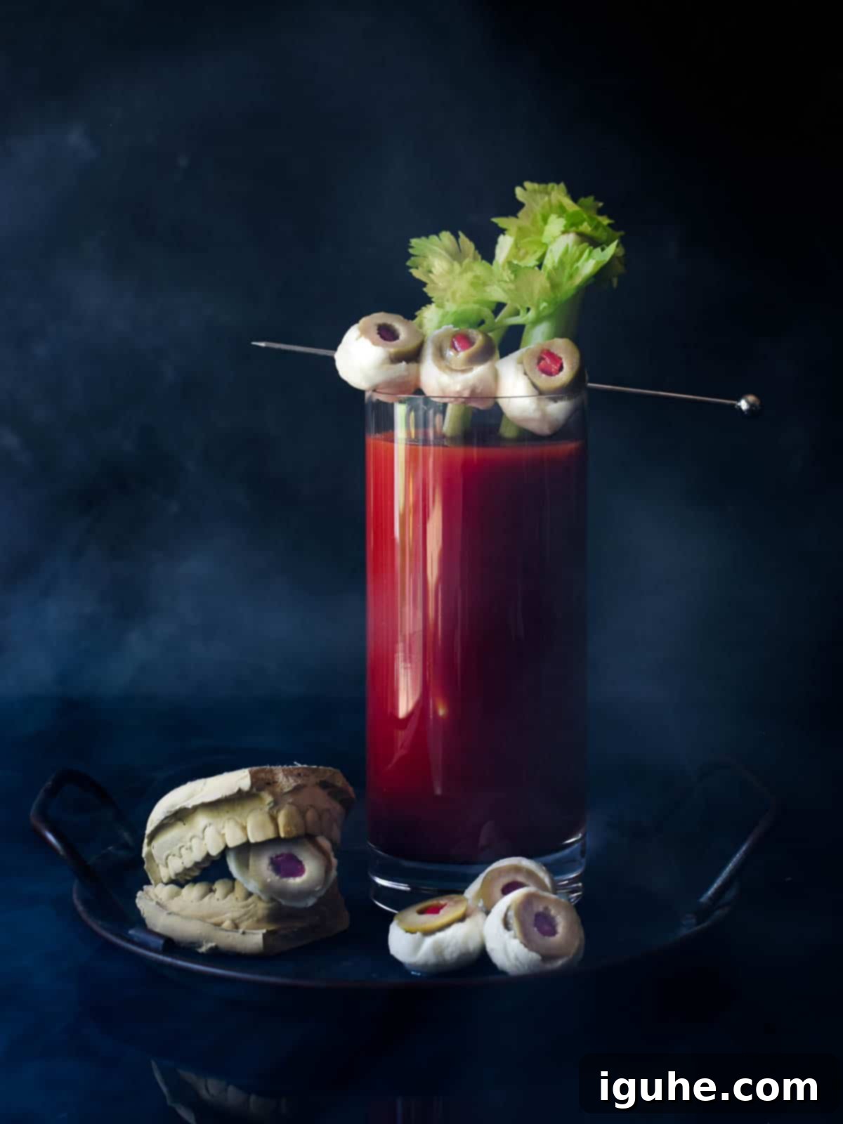Halloween's Bloody Scary Mary 8 A Halloween Bloody Mary cocktail garnished with a celery stick and three mozzarella and olive eyeballs on a skewer, against a dark background, ready to be served.
