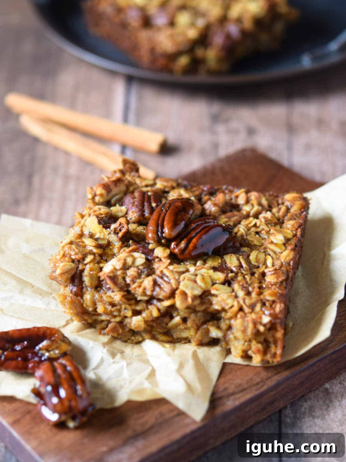 Baked pecan pie oatmeal on a wood slab with cinnamon sticks in the background, evoking a cozy fall feeling.