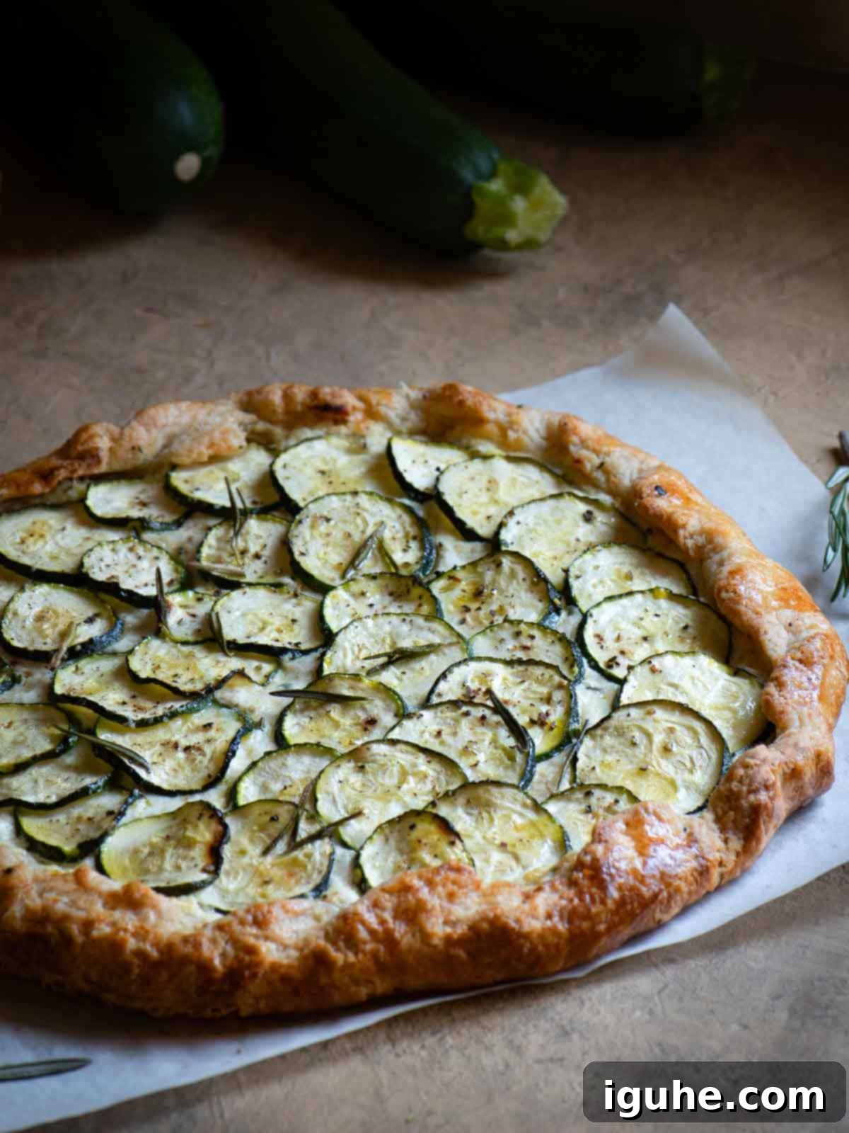 Rustic Zucchini Ricotta Tart 7 Zucchini gallete on a brown surface with zucchini in the background.