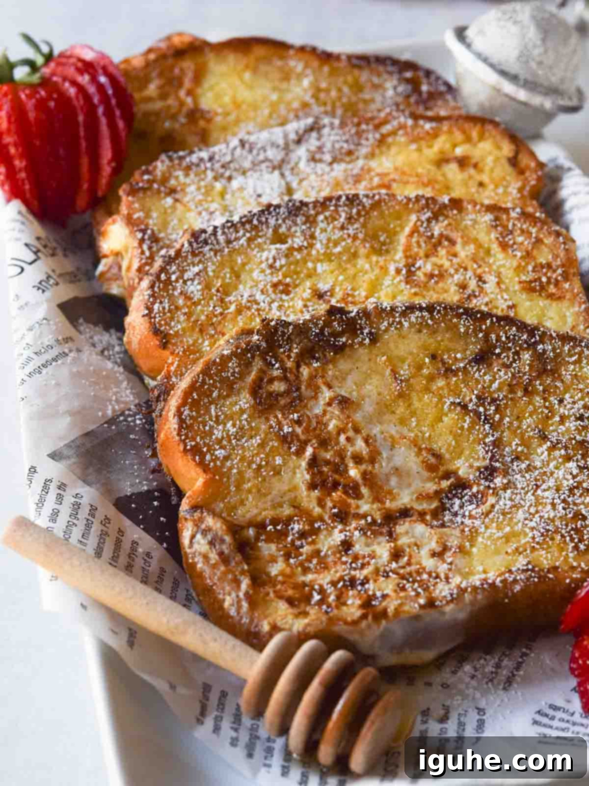Stacked Buttermilk French Toast slices, drizzled with syrup and topped with fresh berries, on a white plate.