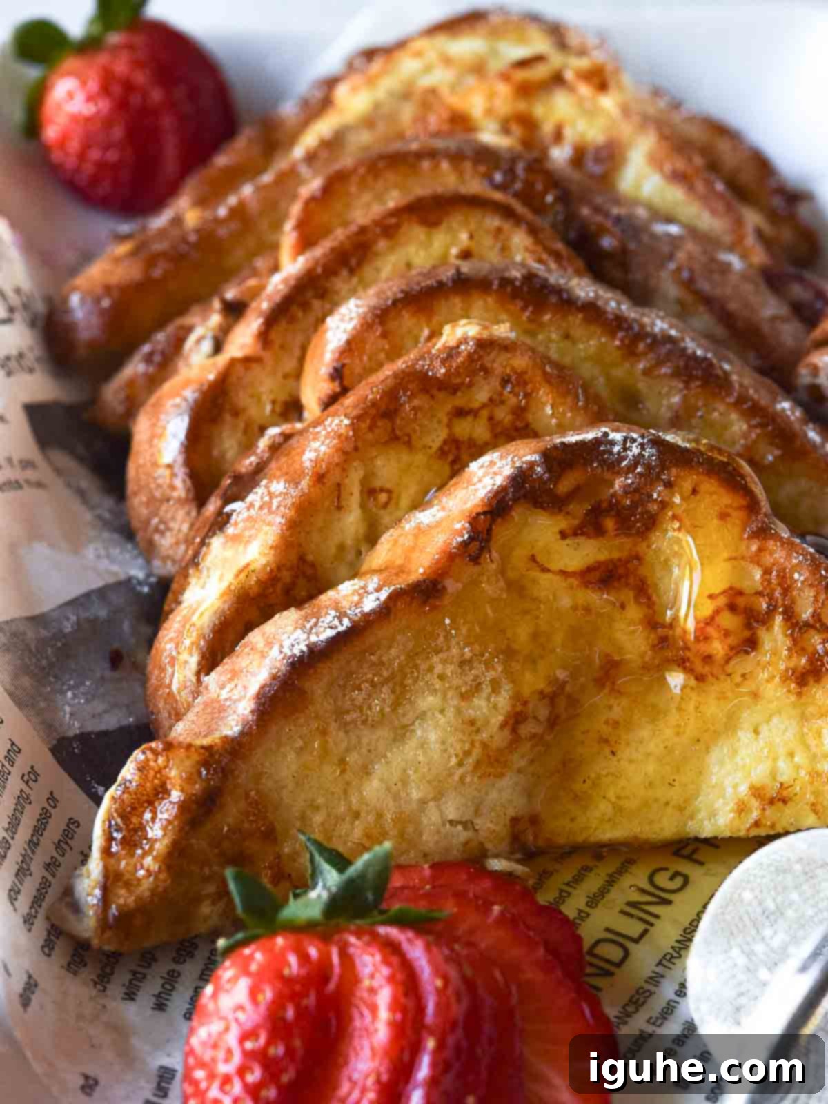 Repurposed Buttermilk French Toast 12 A stack of golden brown buttermilk French toast slices on a white plate, ready to be served.